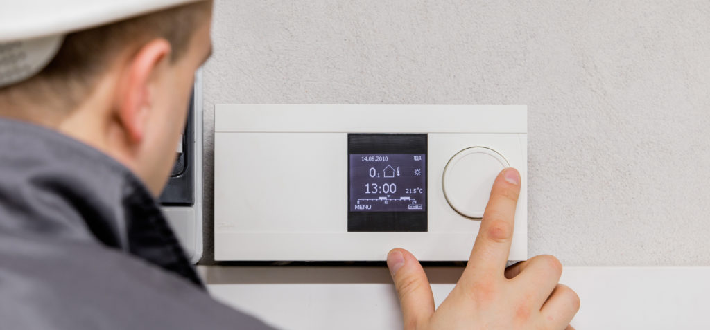 Engineer adjusting thermostat for efficient automated heating sy